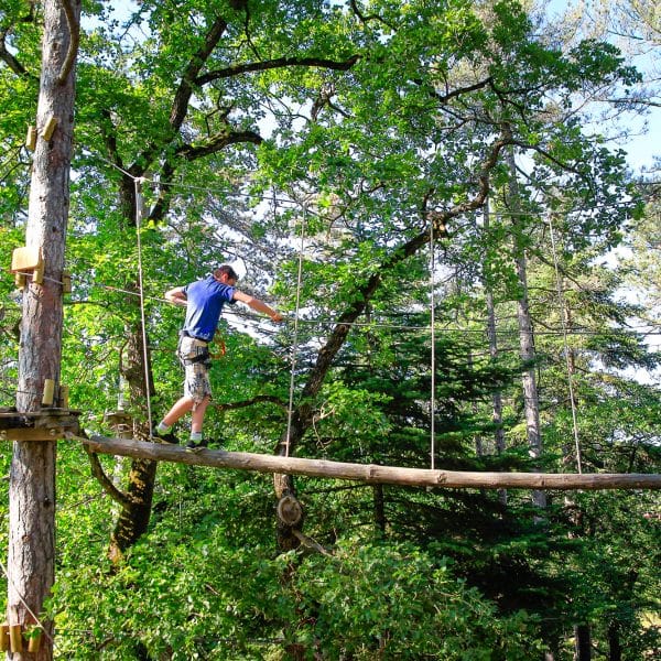 Personne sur une passerelle d'un parcours accrobranche à Die