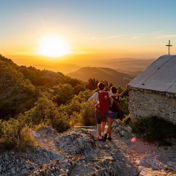 Coucher de soleil à La Chapelle Saint Médart avec un couple qui contemple la forêt de Saoû dans la Vallée de la Drôme