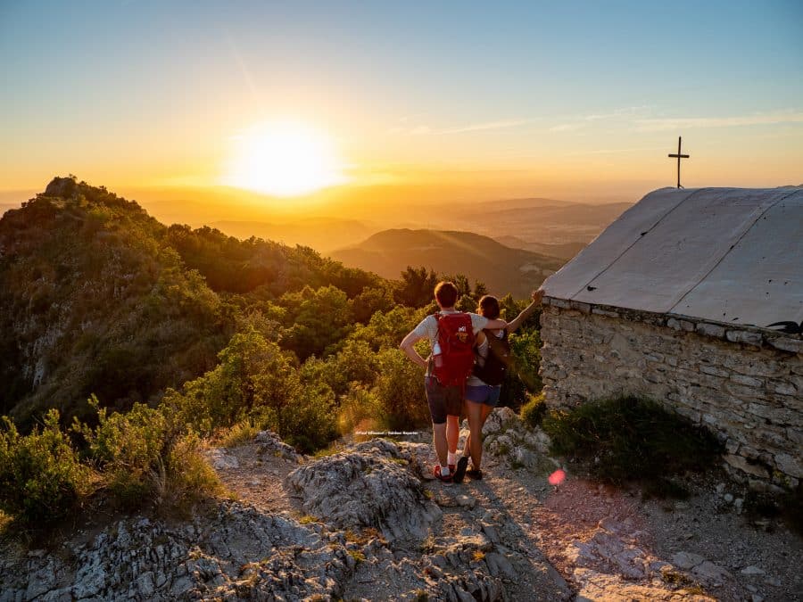 Coucher de soleil à La Chapelle Saint Médart avec un couple qui contemple la forêt de Saoû dans la Vallée de la Drôme